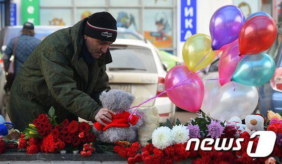 본문 이미지 - 러시아에서 어린 소녀가 죽은 살해 사건 현장에 한 남성이 인형을 두고 있다.ⓒ AFP=뉴스1