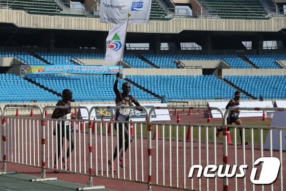 본문 이미지 - 청양군청 소속인 윌슨 로야냐에 에루페(28‧케냐)가 자신이 세운 종전 기록을 갈아치우면서 우승을 차지했다. 사진은 에루페선수가 우승후 청양군청기를 들고 운동장을 돌고 있다.ⓒ News1