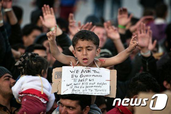 본문 이미지 - 그리스 키오스 섬의  항구에서 한 난민 어린이가 “터키는 싫어요” 라는 구호를 외치고 있다. 난민들은 유럽연합(EU)과 터키의 합의에 따라 키오스 섬을 포함한 5개의 에게섬 난민센터에 분산 수용돼 있다.ⓒ AFP=뉴스1 ⓒ News1
