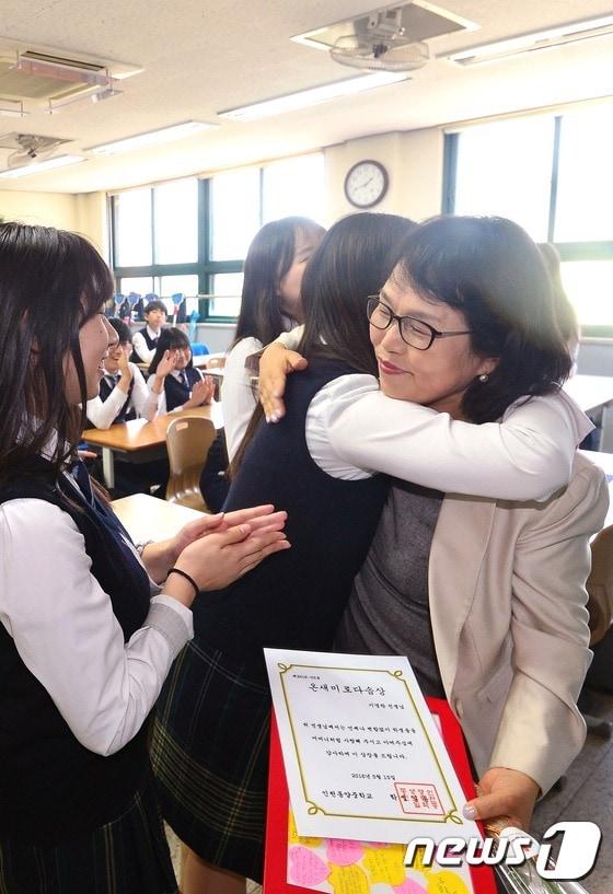 본문 이미지 - 제13회 신일스승상을 수상한 인천 동양중학교 이경란 교사가 스승의 날을 이틀 앞둔 13일 오후 인천 계양구 동양중학교에서 학생들로부터 기념품과 상장을 받은 뒤 포옹하고 있다. 신일스승상은 신일학원 설립자인 고 이봉수 이사장의 뜻에 따라 교육현장을 굳게 지키고 있는 교사들의 노고에 보답하기 위해 지난 2002년 제정됐다.2016.5.13/뉴스1 ⓒ News1 민경석 기자