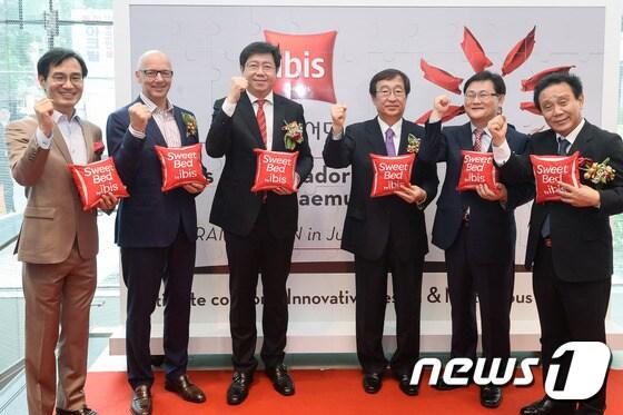 본문 이미지 - 패트릭 바셋 아코르호텔그룹 아시아지역 최고운영책임자(왼쪽 두번째), 서정호 아코르 앰배서더 코리아 회장(왼쪽 세번째)을 비롯한 참석자들이 30일 서울 을지로5가 네거리에 오픈한 이비스 앰배서더 서울 동대문에서 오픈을 축하하는 대형 퍼즐 방명록 앞에서 호텔을 상징하는 빨간 쿠션을 들고 포즈를 취하고있다.ⓒ News1