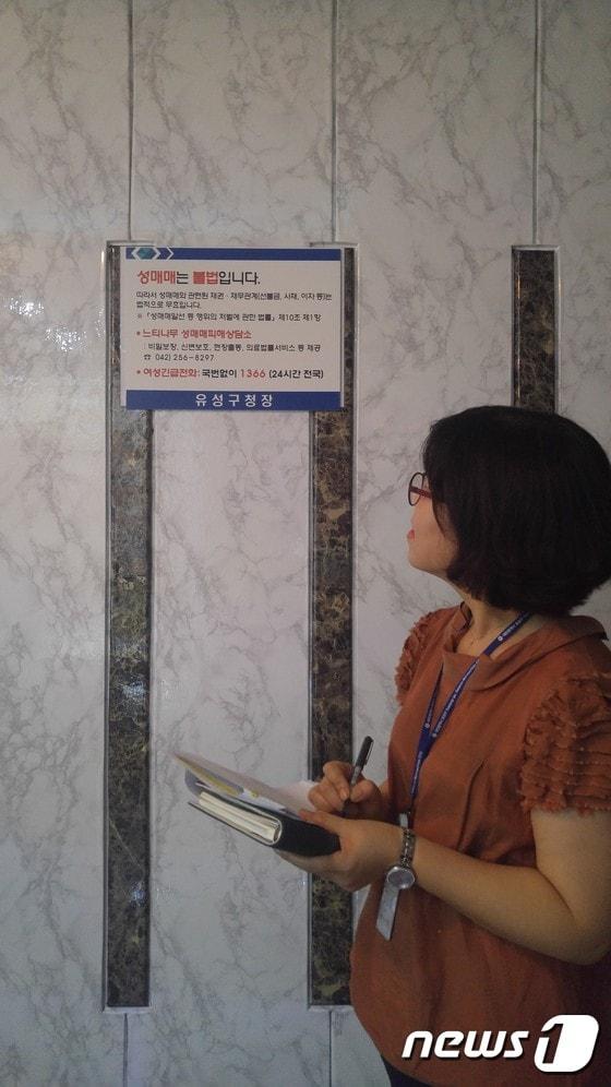 본문 이미지 - 유흥주점에 붙어있는 게시물을 확인하고 있는 모습.ⓒ News1