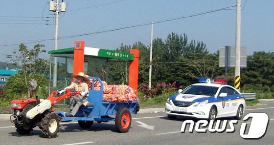 본문 이미지 - 국도5호선에서 농기계사고 예방을 위해 느린속도로 운행중인 경운기를 경찰순찰차가 에스코트하고 있다(사진은 기사와 관련없음)/뉴스1 DB