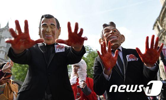 본문 이미지 - 2016년 7월 6일&#40;현지시간&#41; 영국 런던 &#39;퀸 엘리자베스 2세 컨퍼런스 센터&#40;QEII Centre&#41; 밖에서 토니 블레어 전 영국 총리와 조지 W 부시 전 미국 대통령의 가면을 쓴 시위대가 이라크전쟁 관련 보고서 발표를 기다리고 잇다. ⓒ AFP=뉴스1 ⓒ News1 최종일 기자