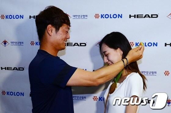 본문 이미지 - 올림픽 사상 첫 전관왕의 위업을 달성한 대한민국 양궁대표팀의 이승윤 선수가 16일 오전 인천국제공항을 통해 귀국, 깜짝 결혼 발표 후 마중 나온 피앙세 김소율씨에게 금메달을 전달하고 있다. 2016.8.16/뉴스1 ⓒ News1 박지혜 기자