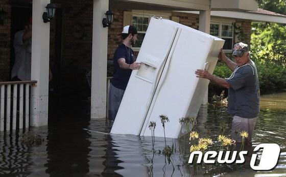 본문 이미지 - 기록적 폭우가 강타한 미국 루이지애나에서 18일(현지시간) 피해 복구 작업이 진행중이다. 지난 12일부터 이어진 폭우로 최소 13명이 숨지고 4만여채의 가옥이 침수됐다. ⓒ AFP=뉴스1