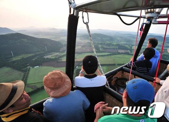 본문 이미지 -  제주패스와 ㈜오름열기구투어 관계자들이 열기구에 탑승해 제주시 구좌읍 상공에서 시험비행을 하고 있다. 이 열기구는 16인승으로 이르면 다음 주 동북아시아 최초로 열기구 관광 상품으로 선보일 예정이다. 뉴스1 ⓒ News1 이석형 기자
