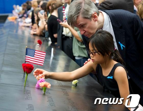 본문 이미지 - 한 소녀가 미국 뉴욕 맨해튼에 있는 9·11 기념박물관의 추모비를 들여다보고 있다. 9.11기념박물관은 테러로 폭파된 세계무역센터 쌍둥이 빌딩이 있던 그 자리에 설립됐다. ⓒ AFP=뉴스1