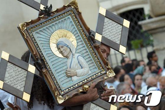 본문 이미지 - '빈자의 성녀' 고(故) 테레사 수녀를 성인으로 추앙하는 4일(현지시간) 바티칸 성베드로 대성당 광장에서 한 남성이 테레사 수녀가 그려진 액자를 들고 있다. ⓒ AFP=뉴스1