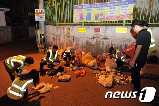 본문 이미지 - 불법 배출된 쓰레기를 분리수거하는 모습(뉴스1 DB) ⓒ News1 박하림 기자