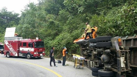 본문 이미지 - 전북 완주군 구이면 염암마을 염재 내리막길 도로에서 벼를 실은 8톤 트럭(운전자 A씨·38)이 전도돼 있는 것을 인근을 지나가던 운전자가 발견해 119에 신고해 출동한 소방대원에 의해 구조작업이 벌어지고 있다.(전주완산소방서 제공)2016.9.7/뉴스1 ⓒ News1 