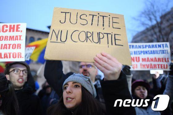 본문 이미지 - 22일(현지시간) 루마니아 수도 부쿠레슈티에서 열린 시위에 참가한 한 여성이 '부패 아닌 정의(Justice not Corruption)'라 적힌 플랜카드를 들고 있다. ⓒ AFP=뉴스1