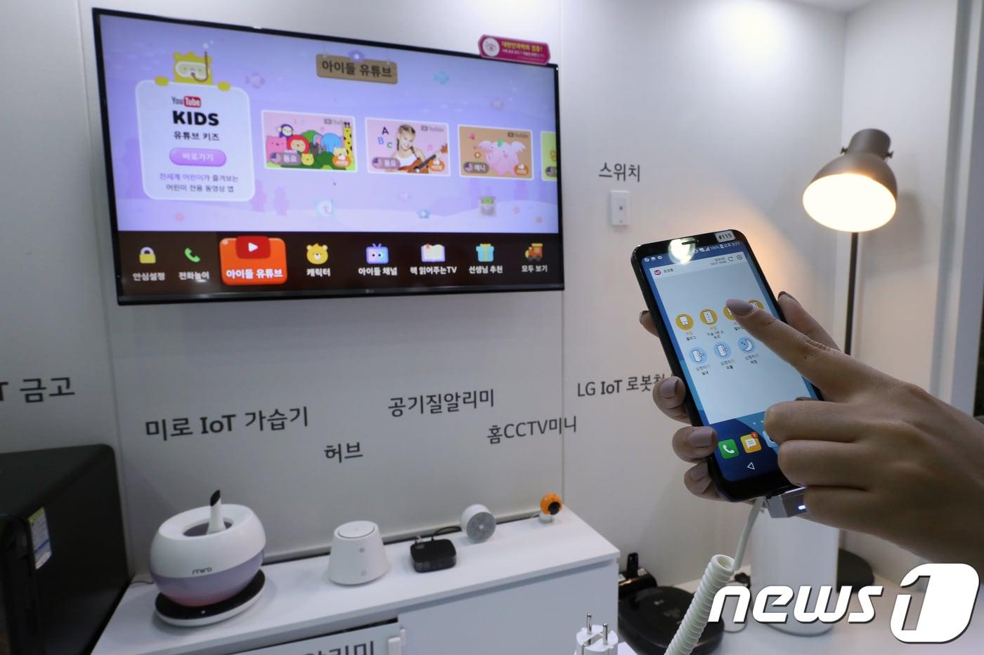 본문 이미지 - 사물인터넷(IoT) 관련 전시회에서 한 직원이 스마트폰을 이용해 집안 내부를 제어하는 사물인터넷(IoT) 기술을 실현하는 모습.  /뉴스1DB