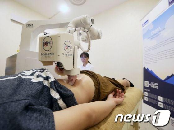 본문 이미지 - 싱가포르의 노바헬스 TCM클리닉에서 환자의 등을 마사지하는 '엠마'ⓒ News1