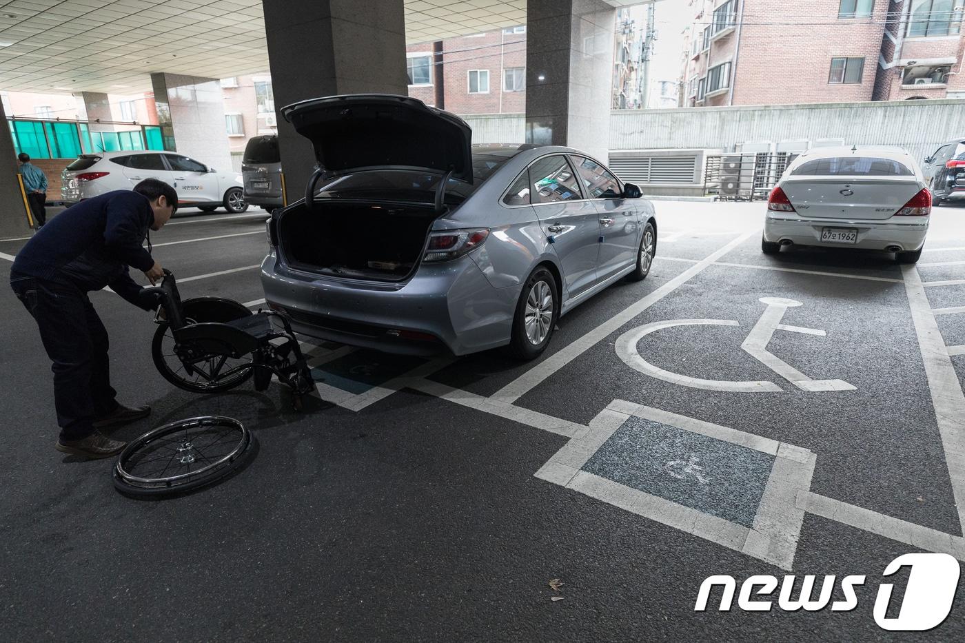 본문 이미지 - 서울 구로구 소재 한 대형빌딩 주차장 장애인전용주차구역에서 한 시민이 휠체어를 내리고 있다.  ⓒ 뉴스1 유승관 기자