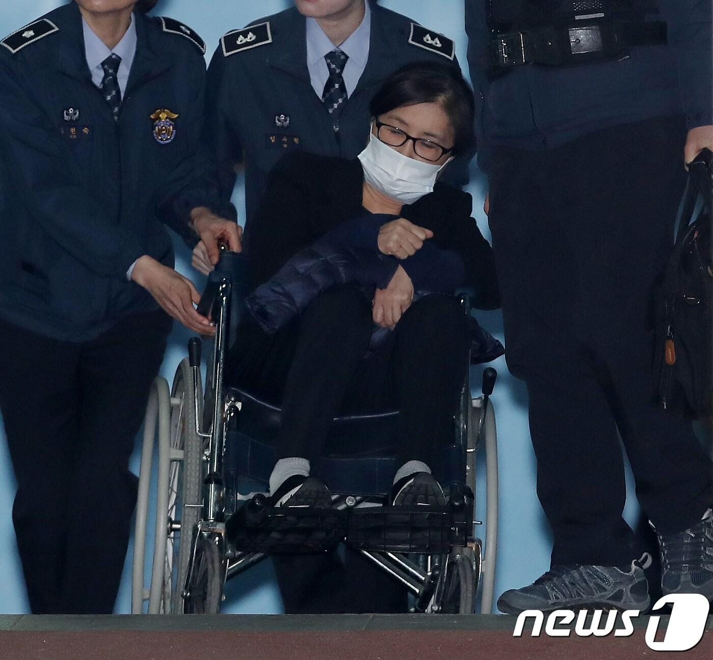 본문 이미지 - '비선실세' 최순실 씨가 14일 오후 서울중앙지방법원에서 열린 직권남용권리행사방해 등 결심공판을 마친 뒤 휠체어를 타고 호송차로 향하고 있다. 2017.12.14/뉴스1 ⓒ News1 민경석 기자