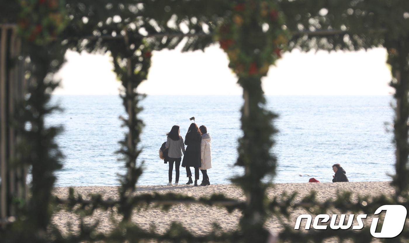 부산 해운대해수욕장을 찾은 관광객들이 성탄절을 맞아 설치 중인 크리스마스트리뒤로 관광객들이 바다를 바라보고 있다. ⓒ News1 여주연 기자