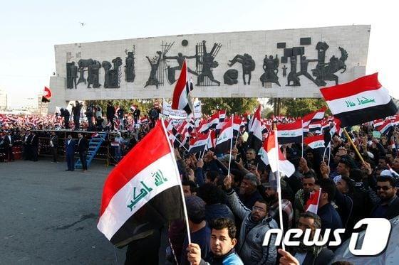 본문 이미지 - 이라크 정치제도 개혁을 요구하는 시위대가 11일(현지시간) 바그다드 타히르 광장에서 국기를 들고 있다. ⓒ AFP=뉴스1