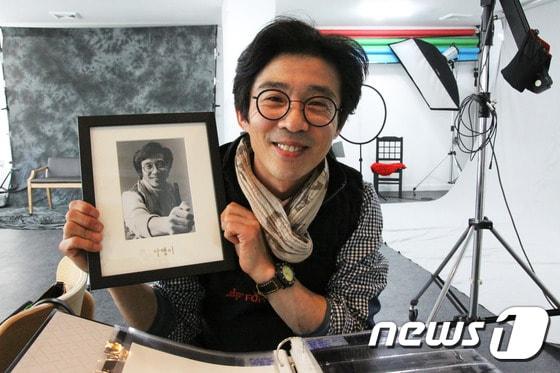 본문 이미지 - 충남유일의 흑백필름사진관인 '달팽이사진관' 황재철대표가 자신이 직접 찍은 본인사진을 들고  웃고 있다.ⓒ News1