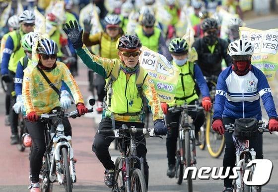 본문 이미지 - 녹색자전거봉사단연합 소속 자전거 동호인들이 9일 서울 서초구 반포한강공원에서 열린 2017 자전거안전문화캠페인 및 시륜제를 마친 뒤 '과속 NO, 헬멧 YES'라고 적힌 안전구호 깃발을 달고퍼포먼스를 펼치고 있다. 2017.3.9/뉴스1 ⓒ News1 오대일 기자