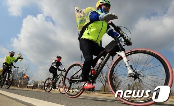본문 이미지 - 녹색자전거봉사단연합 소속 자전거 동호인들이 9일 서울 서초구 반포한강공원에서 열린 2017 자전거안전문화캠페인 및 시륜제를 마친 뒤 '과속 NO, 헬멧 YES'라고 적힌 안전구호 깃발을 달고 퍼포먼스를 펼치고 있다. 2017.3.9/뉴스1 ⓒ News1 오대일 기자