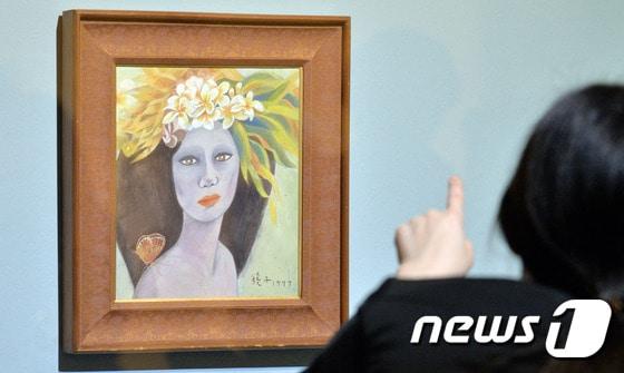 본문 이미지 - 18일 경기도 과천 국립현대미술관에서 관계자가 고&#40;故&#41; 천경자&#40;1924∼2015&#41; 화백의 작품인지를 놓고 논란이 계속되는 &#39;미인도&#39;를 바라보고 있다. 2017.4.18/뉴스1 ⓒ News1 김명섭 기자