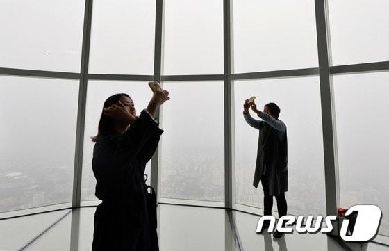 본문 이미지 - 6일 오후 서울 송파구 롯데월드타워 전망대에서 시민들이 안개 낀 서울을 배경으로 '셀카'를 찍고 있다. 기상청은 "전국이 대체로 흐리고 중부서해안과 일부 내륙에 안개가 짙게 낀 곳이 있다＂며 주의를 당부했다.2017.4.6/뉴스1 ⓒ News1 구윤성 기자