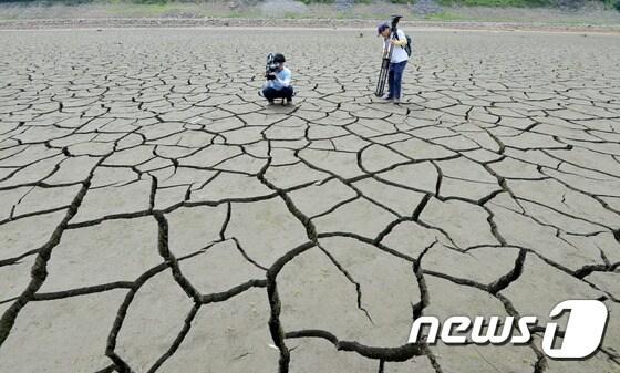 본문 이미지 - 지난 2017년 충남 보령댐 상류에서 한 취재진이 계속되는 가뭄으로 바싹 말라 바닥을 드러낸 모습을 취재하고 있다. 2017.5.30/뉴스1 ⓒ News1 주기철 기자
