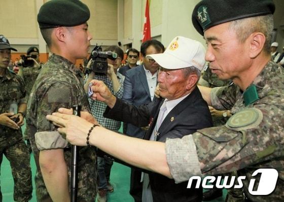 본문 이미지 - 1일 연천수레울체육관에서 열린 육군28사단 신병수료식에서 참전용사가 윤의철 사단장(사진 오른쪽)과 함께 신병에게 태극기를 달아주고 있다. 사진제공=육군제28사단 ⓒ News1