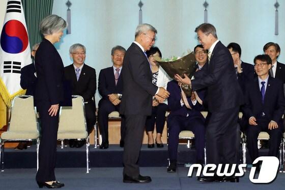 본문 이미지 - 문재인 대통령이 18일 오후 청와대에서 열린 강경화 외교부장관 임명식에서 강 장관의 남편인 이일병 교수에게 꽃다발을 주고 있다.(청와대) 2017.6.18/뉴스1 ⓒ News1 이광호 기자
