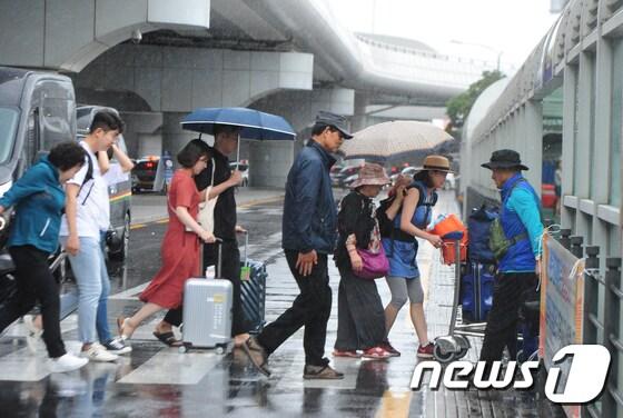 본문 이미지 - 29일 제주시 제주국제공항에서 공항 이용객들이 비를 피해 발걸음을 재촉하고 있다. 2017.6.29/뉴스1 ⓒ News1 이석형 기자