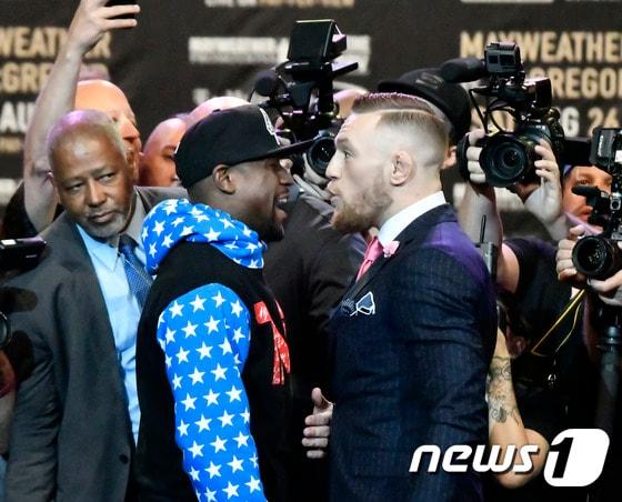 본문 이미지 - 코너 맥그리거(오른쪽)와 플로이드 메이웨더가 12일(한국시간) 미국 로스앤젤레스의 스테이플스 아레나에서 열린 기자회견에서 신경전을 펼치고 있다. ⓒ AFP=News1