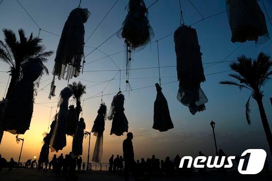 본문 이미지 - 레바논 수도인 베이루트의 코니쉬 해안가에 줄에 묶인 웨딩 드레스 수십벌이 전시돼 있다. 이는 강간범이 강간 피해자와 결혼할 경우 기소 면책권을 주는 '형법 522조' 폐지를 촉구하는 비정부기구(NGO) 아바드의 여성 인권 캠페인이다. ⓒ AFP=뉴스1