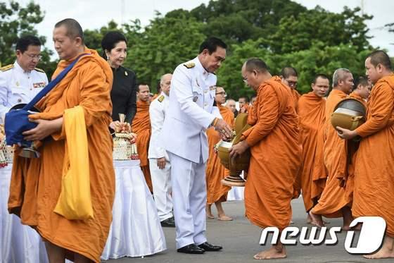 본문 이미지 - 프라윳 찬 오차 총리 태국 총리가 국왕탄신일을 맞은 28일 방콕에 있는 로열플라자에서 탁발승려들에게 보시하고 있다. ⓒ AFP=뉴스1