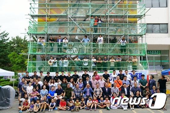 본문 이미지 - 19일 전남대 사범대 1호관 벽에 그려진 '광주민중항쟁도' 복원 작업에 앞서 벽면에 가설제 구조물을 설치하고 참여 작가와 시민들이 기념촬영을 하고 있다.(추진위 제공)2017.8.20/뉴스1 ⓒ News1 박준배 기자