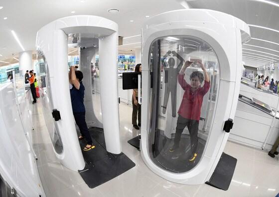 본문 이미지 - 14일 오전 정식 개장을 목전에 둔 인천공항 제2여객터미널에서 열린 종합 시험운영 점검에서 가상 여행객들이 전신검색대를 통과하고 있다. 원형검색대는 기존의 문형(門形) 금속탐지 검색대로 검색할 수 없는 비금속이나 신체 속에 숨겨둔 물품을 탐지할 수 있는 장비다. 2017.9.14/뉴스1 ⓒ News1 오대일 기자