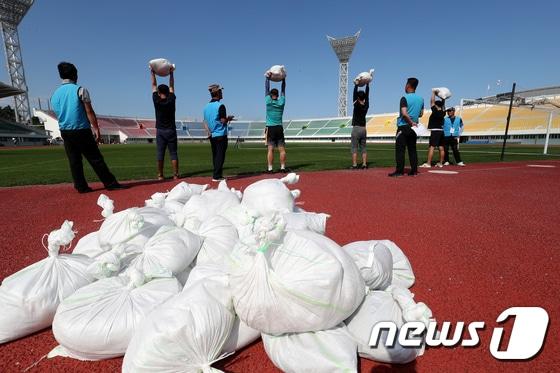 본문 이미지 - 14일 강원도 강릉시 종합운동장에서 진행된 환경미화원 공개 채용 체력시험에 참가한 남자 응시자들이 검정 종목 중 하나인 30㎏ 모래주머니 들고 버티기를 치르고 있다. 2017.9.14/뉴스1 ⓒ News1 서근영 기자