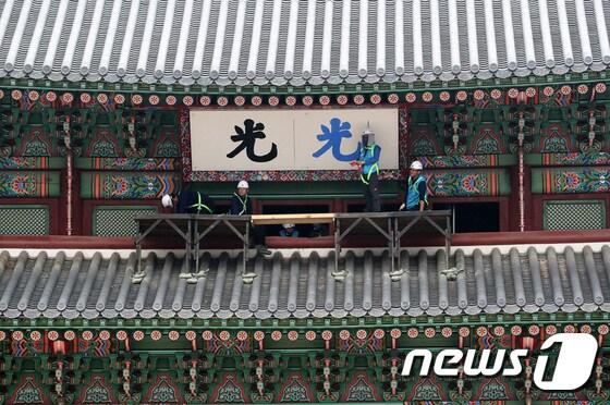 본문 이미지 - 문화재청 직원들이 지난 9월27일 서울 광화문에서 광화문 현판 색상 분석 연구를 위한 실물 크기 실험용 현판을 설치하고 있다. 이 작업은 약 100년 전에 촬영된 흑백사진 속 광화문의 현판 색상을 찾아내기 위한 것으로 수년간 이어진 광화문 현판 논란을 해소하기 위한 작업이다. /뉴스1 ⓒ News1