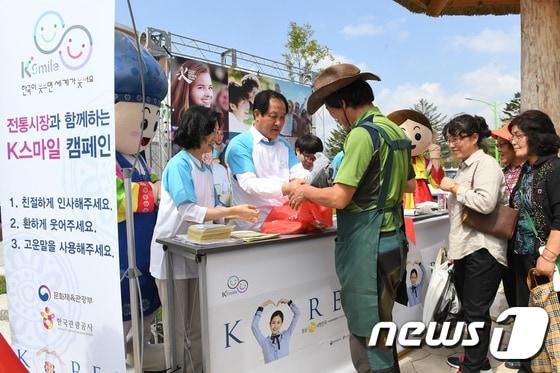 본문 이미지 - 평창효석문화제가 열리고 있는 7일 강원 평창군 봉평면 봉평전통시장에서 한국관광공사, 평창군, 봉평전통시장상인회가 함께하는 K스마일 친절캠페인이 열린 가운데 심재국 평창군수(가운데)와 강옥희 관광공사 국제관광진흥본부장(왼쪽)이 상인들을 대상으로 진철 봉지를 나눠주고 있다.(평창군 제공).2017.9.7/뉴스1 ⓒ News1 권혜민 기자