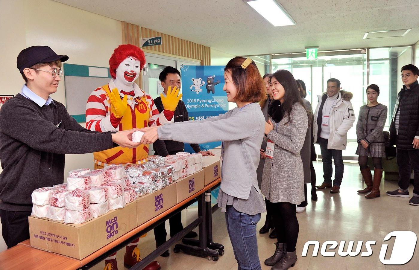 본문 이미지 - 맥도날드 직원들과 마스코트 로날드 맥도날드가 2018 평창 동계올림픽 자원봉사자들에게 햄버거를 전달하고 있다. ⓒ News1