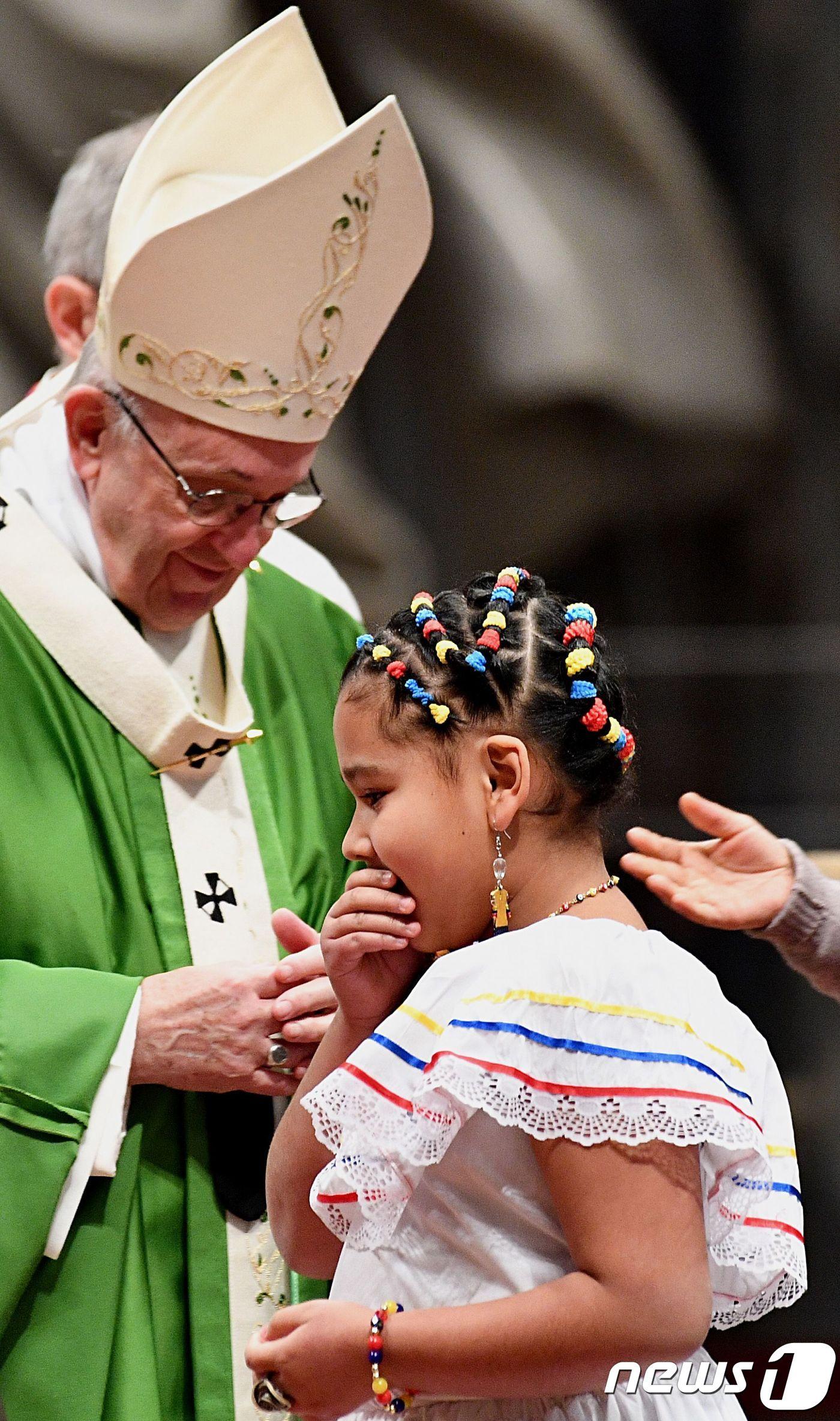 본문 이미지 - 프란치스코 교황이 14일(현지시간) 세계 이민·난민의 날을 맞아 바티칸 성베드로 대성전에서 특별미사를 집전하면서 난민 소녀를 위로하고 있다. 프란치스코 교황은 이날 특별미사에서 난민·이주민 수용을 거부하는 것은 죄악이라며 포용을 촉구했다. ⓒ AFP=뉴스1 ⓒ News1 우동명 기자