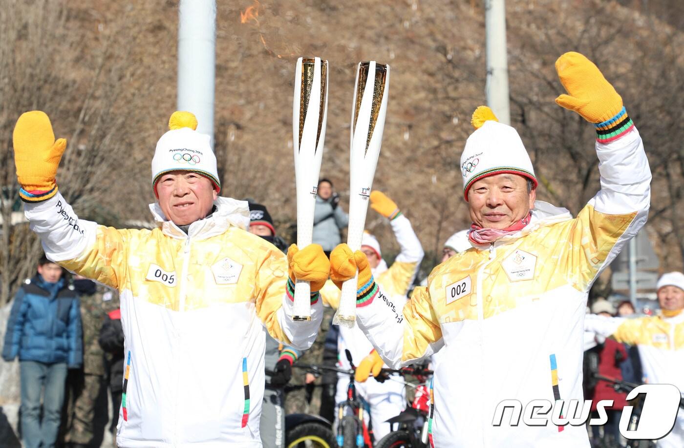 본문 이미지 - 25일 강원도 인제군 서화면 서화생활체육공원에서 출발한 자전거 성화 봉송팀 조인태씨(왼쪽)와 김태호씨가 북면 원통리 북면사무소 앞에서 기념촬영하고 있다. 강원도 내 올림픽 성화봉송은 내달 9일까지 18개 시·군 지역에서 구간별로 펼쳐진다. 2018.1.25/뉴스1 ⓒ News1 고재교 기자