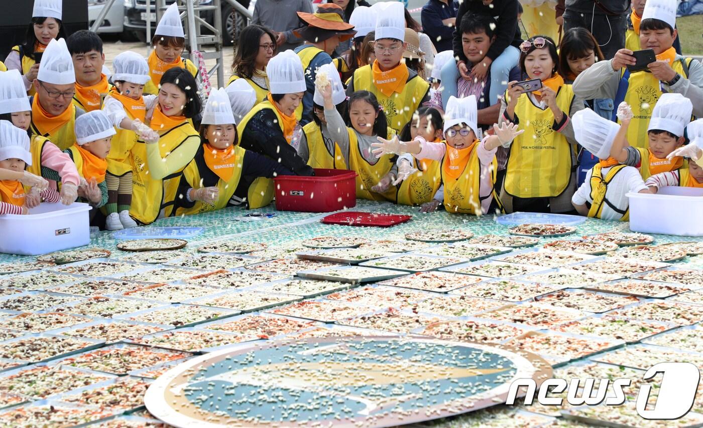 본문 이미지 - 지난해 10월8일 전북 임실군 임실치즈테마파크에서 열린 '2018 임실N치즈축제'에서 어린이들이 국가대표 왕 치즈피자 만들기 체험에 참가해 피자 위에 치즈를 뿌리고 있다. 2018.10.8/뉴스1 ⓒ News1 문요한 기자