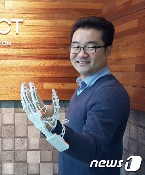 본문 이미지 - ‘문재인 글러브’로 알려진 재활용 의료용기를 제조하는 ㈜네오펙트가 2014년 단국대 차세대녹색기술창업플라자센터에 입주한 지 4년 만에 오는 28일 코스닥에 상장된다. 사진은 ㈜네오펙트 반호영대표가 '문재인 글로브'로 알려진 라파엘 스마트 글러브를 착용한 모습.(단국대 제공) ⓒ News1 김평석 기자