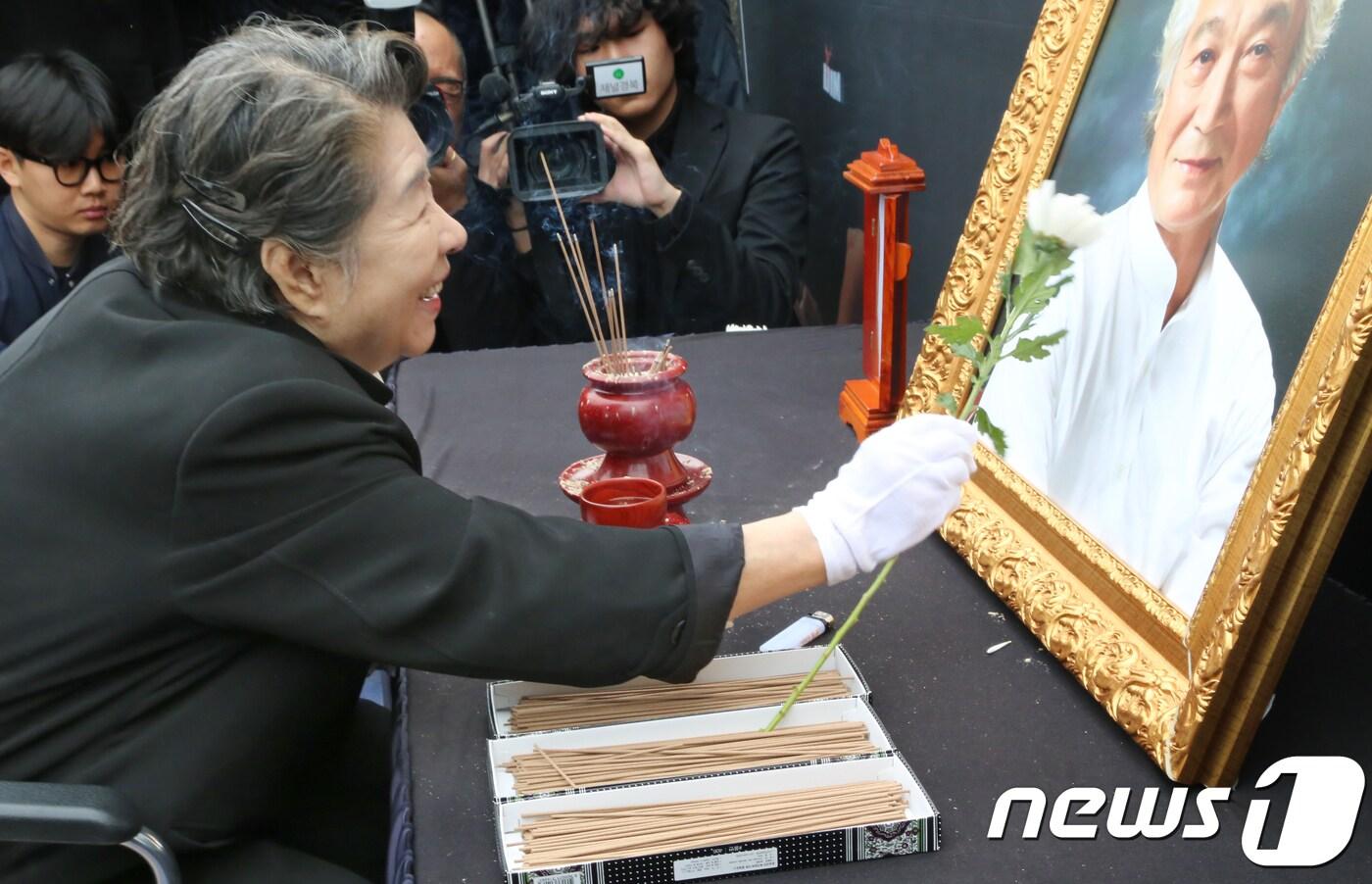 본문 이미지 - 7일 경북 영천시 괴연동 성일가에서 열린 故 신성일 추모제에서 부인 엄앵란씨가 신성일씨의 영정을 흰국화로 쓰다듬고 있다. 고인의 유언에 따라 그의 유해는 자신이 살던 집 앞 마당에 묻혔다. 故신성일은 60-70년대 은막을 주름잡았던 한국 최고의 영화배우이자 국민배우로 그가 출연한 영화만 500편이 넘는다.2018.11.7/뉴스1 ⓒ News1 정우용 기자