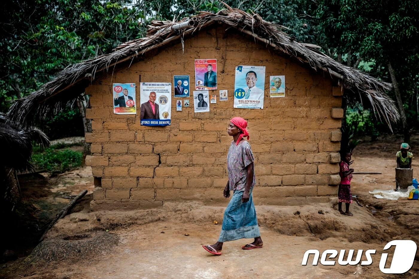 26일(현지시간) 콩고민주공화국 중부 본디 지역 인근 길가에 붙은 대통령 선거 벽보 앞으로 한 여성이 지나가고 있다. ⓒ AFP=뉴스1