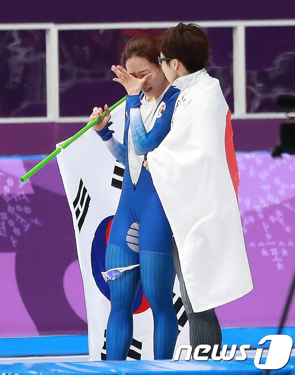 본문 이미지 - 대한민국 이상화가 18일 강원도 강릉 스피드스케이팅 경기장 오벌에서 열린 2018 평창동계올림픽 스피드 스케이팅 여자 500m 경기를 마치고 국기 세리머니 중 눈물을 흘리자 고다이라 나오(일본)가 위로하고 있다. 이상화는 이날 37초33으로 은메달을 획득했다.2018.2.18/뉴스1 ⓒ News1 임세영 기자