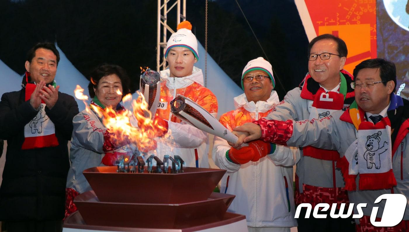 본문 이미지 - 7일 강원 정선군 아라리촌에서 열린 2018평창패럴림픽 성화봉송에서 동계올림픽 스노보드 남자 평행대회전 은메달리스트 정선 출신 ‘배추보이’ 이상호 선수와 김지완 시각장애인정선군지부 회장이 성화대에 불을 붙이고 있다. 2018.3.7/뉴스1 ⓒ News1 박하림 기자
