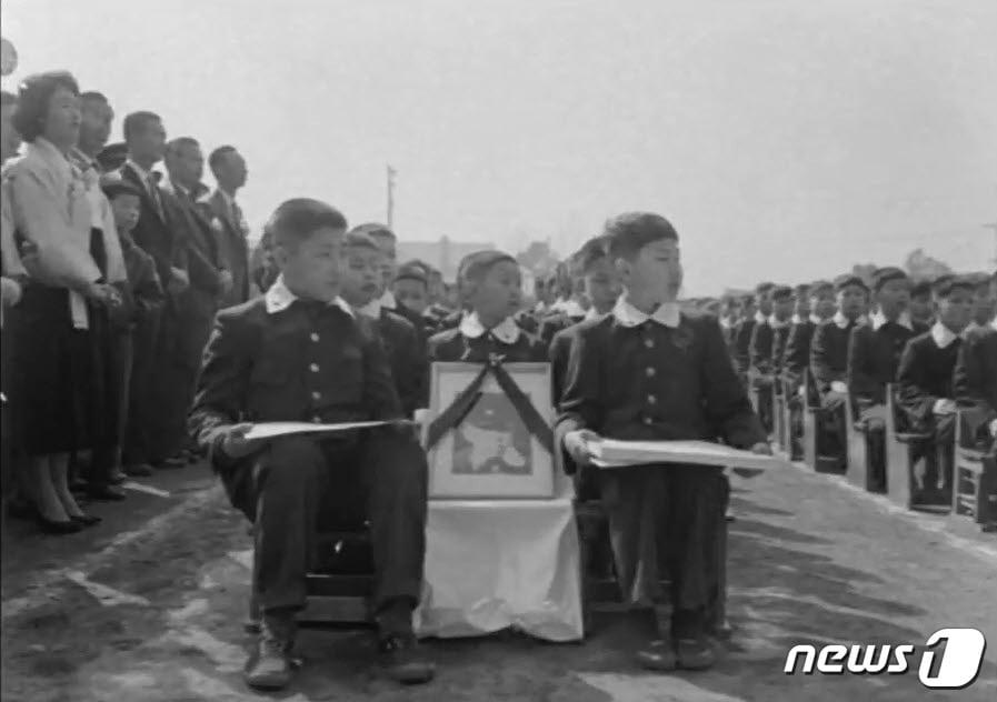 본문 이미지 - 1961년 수송초등학교 졸업식에서 전한승 군의 영정과 졸업생들이 함께 앉아있다(수송초 개교기념일 영상 캡처) ⓒ News1