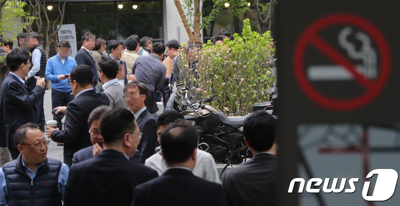 본문 이미지 - 서울 종로구 금연 구역 표지판이 세워진 바로 맞은편에 설치된 한 흡연구역에서 흡연자들이 담배를 피우고 있다. 2018.4.24/뉴스1 ⓒ News1 허경 기자